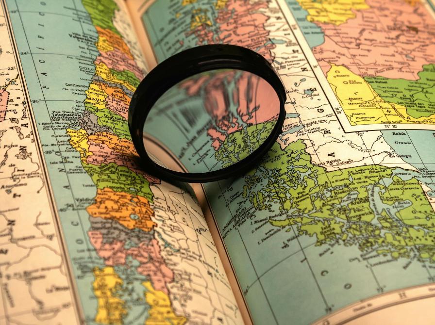 Lup ligger på et opslået kort i en bog og forstørrer detaljer i atlas.