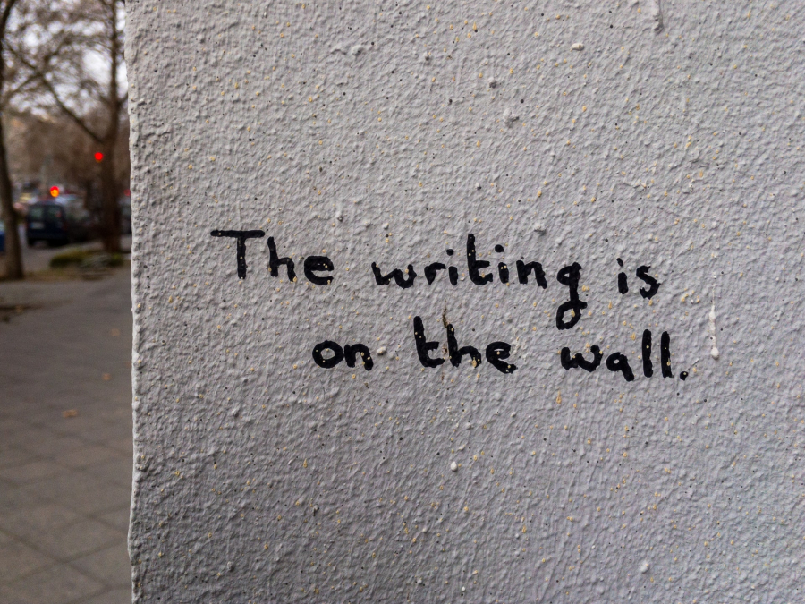 Billede fra Unsplash af mur med teksten "The writing is on the wall"